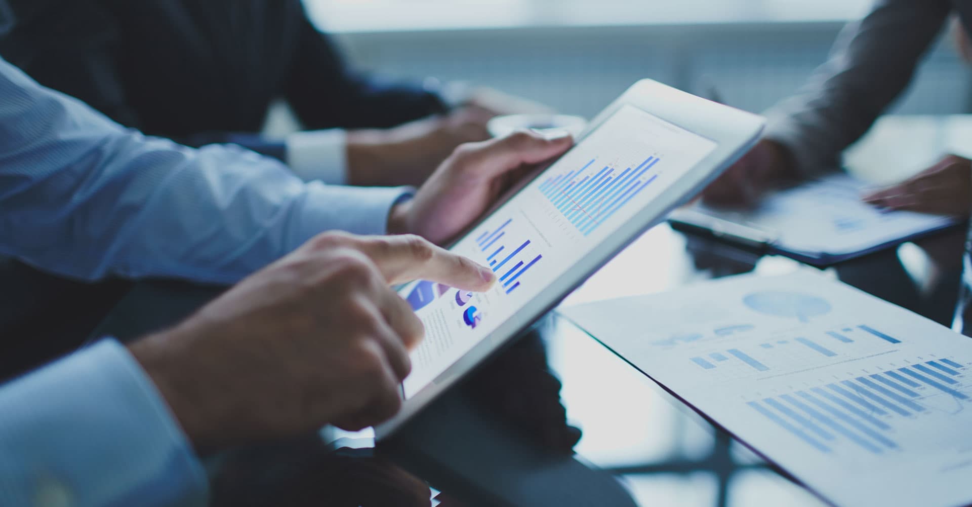 Businessperson pointing at financial charts on a tablet